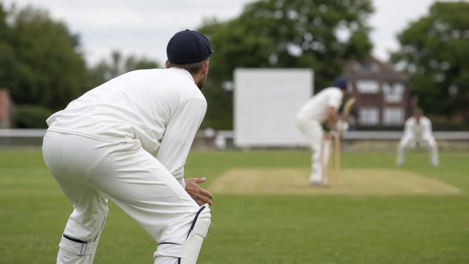 Close sideline view of a slip fielder in pads preparing to react to a delivery